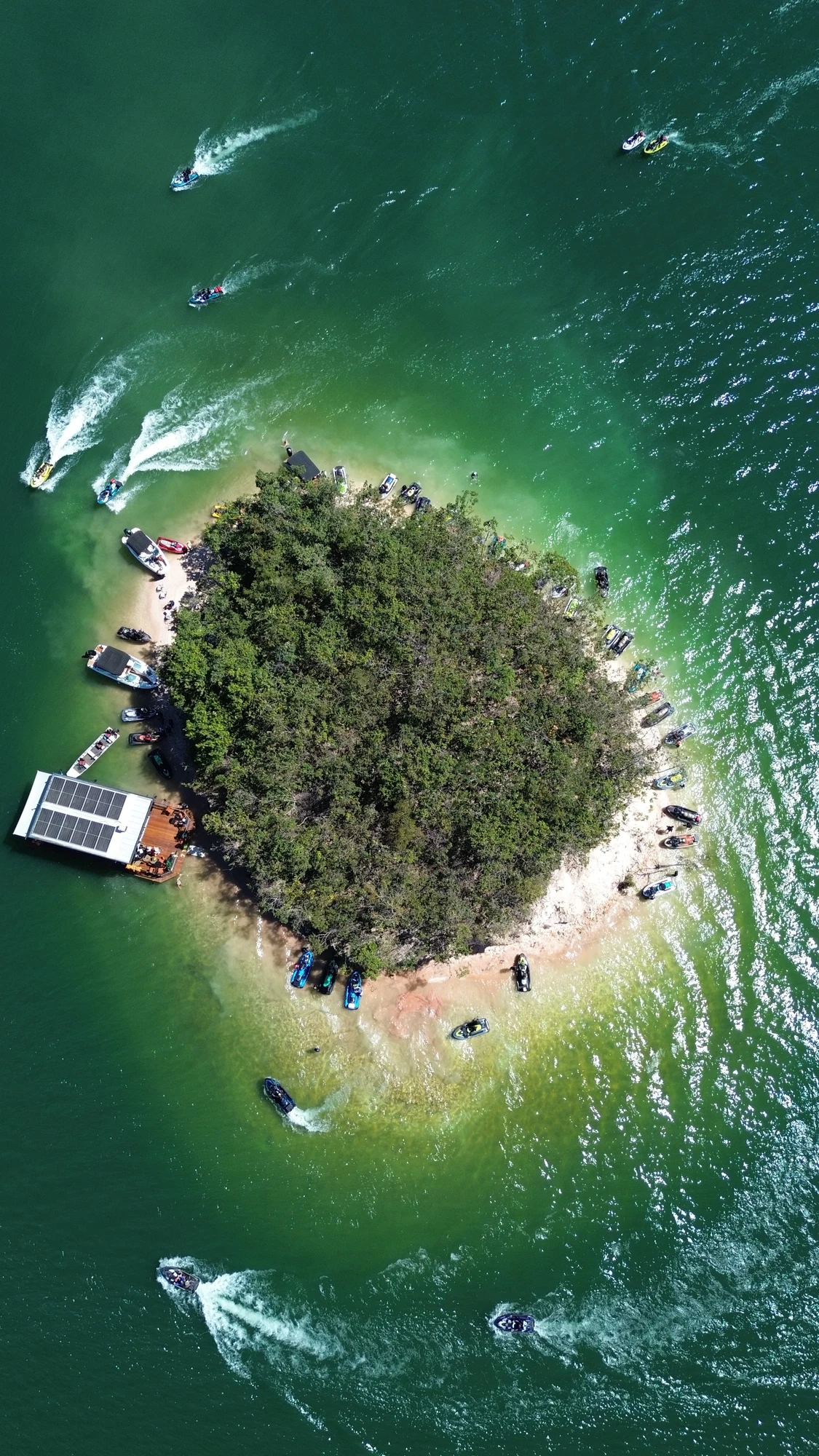 Vista aérea de uma ilha no Lago Corumbá, cercada por barcos e jet skis